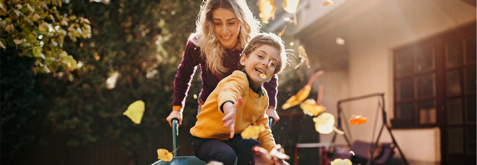 A mom and child playing in fallen leaves