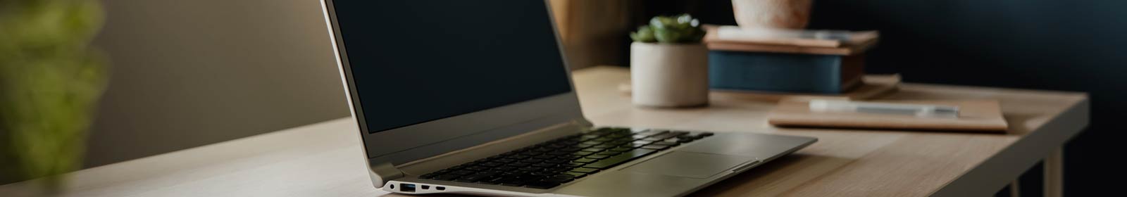 a laptop placed on a table next to a small plant